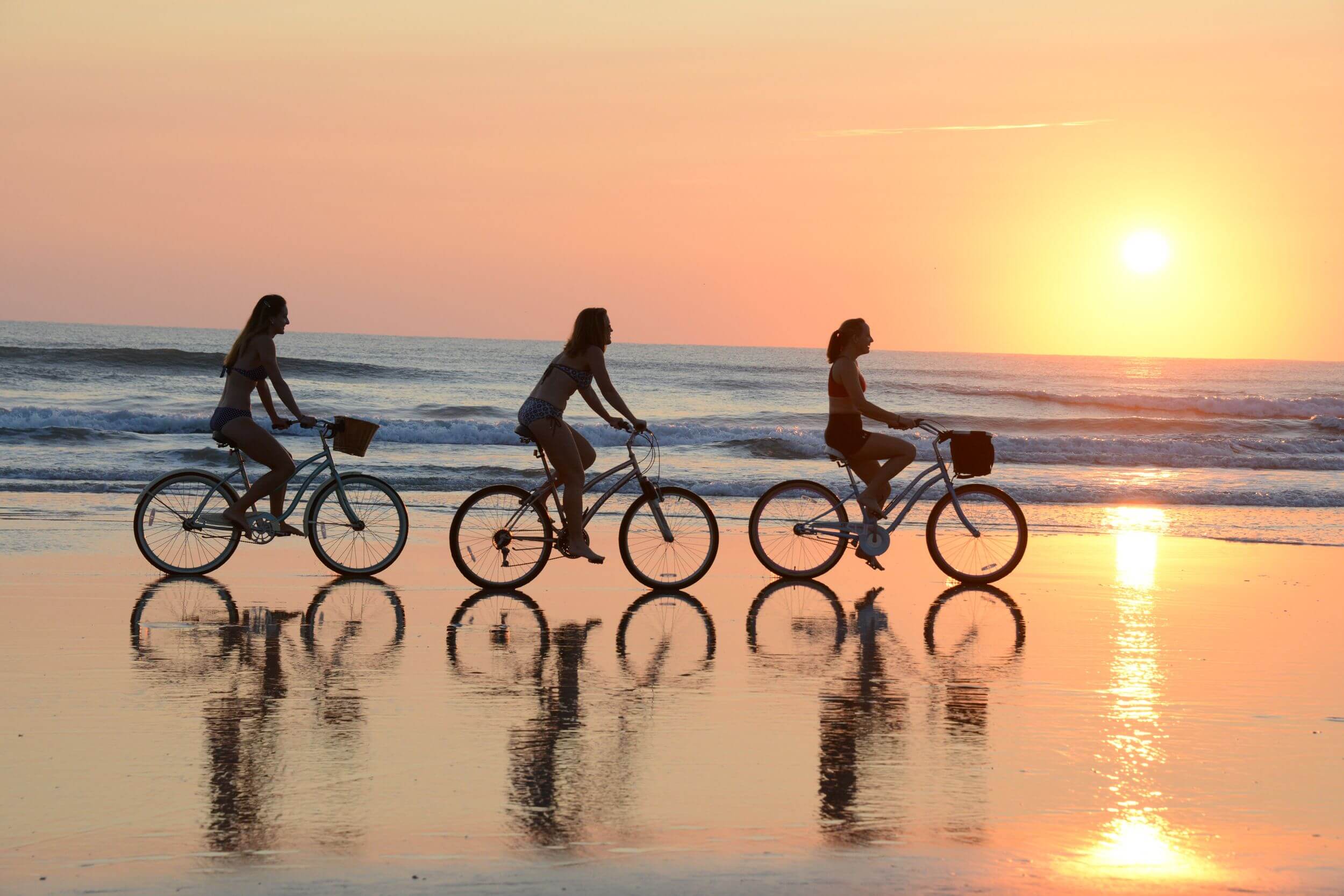 A group of people walking on a beach near a body of water