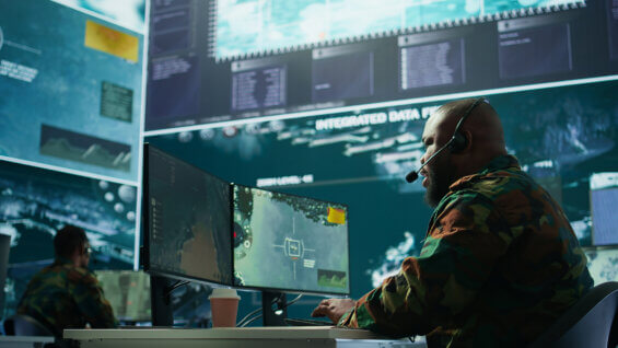Military control room features army personnel monitoring surveillance systems.